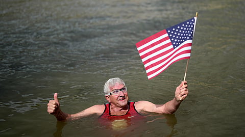 Joel Stratte-McClure, 75, of the US, holds American flag after completing a short swim in the Seine river, Thursday, July 4, 2024 in Paris.