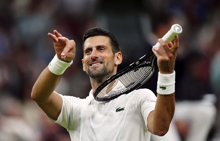 Novak Djokovic of Serbia pretends to play a violin after defeating Holger Rune of Denmark in their fourth-round match at Wimbledon 2024 in London, Monday, July 8, 2024. - Mike Egerton/PA via AP