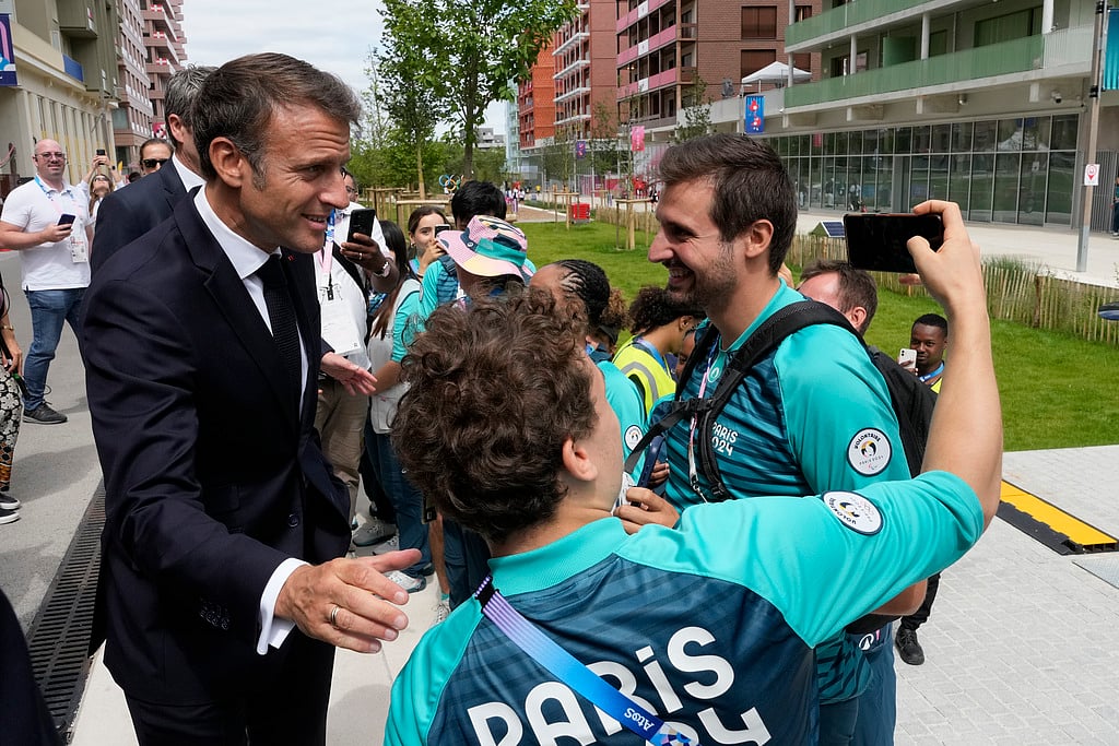 French President Emmanuel Macron poses for a selfie with volunteers as he visits the Olympic Village, at the 2024 Summer Olympics, Monday, July 22, 2024, in Paris, France. - AP