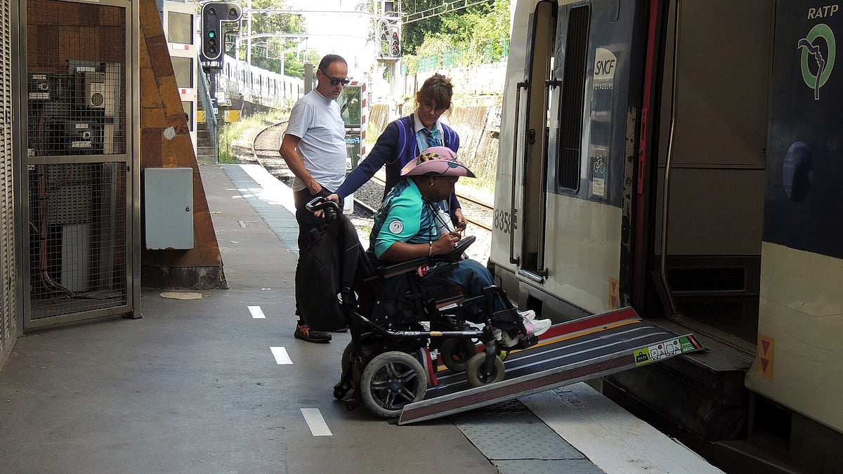 Ndieme Lame, a 57-year-old volunteer for the Paris 2024 Olympic and Paralympic Games navigates a ramp to join a RER train with the help of rail agents, during the 2024 Summer Olympics, Wednesday, Aug. 7 2024, in Paris, France. -  AP Photo/Tom Nouvian