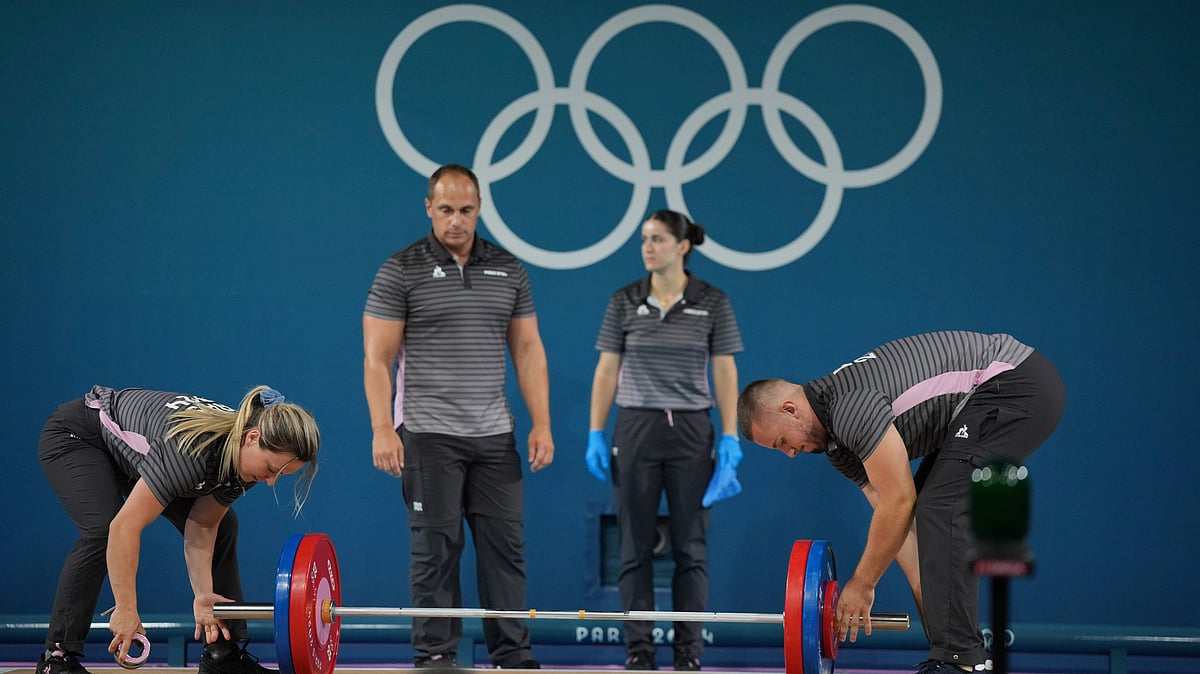 Loaders set the weight on the bar during the women's 59kg weightlifting event at the 2024 Summer Olympics, Thursday, Aug. 8, 2024, in Paris, France. -  AP Photo/Kin Cheung