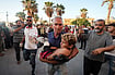 The Price Of Survival: Israel Plays And Palestine Pays With Lives (AP Photo/Abdel Kareem Hana) : A Palestinian man carries an injured child after an Israeli airstrike in Deir al Balah, Gaza Strip, Tuesday, Aug. 6, 2024.