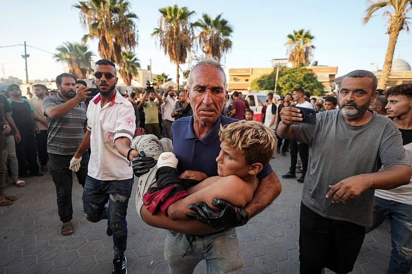 A Palestinian man carries an injured child after an Israeli airstrike in Deir al Balah, Gaza Strip