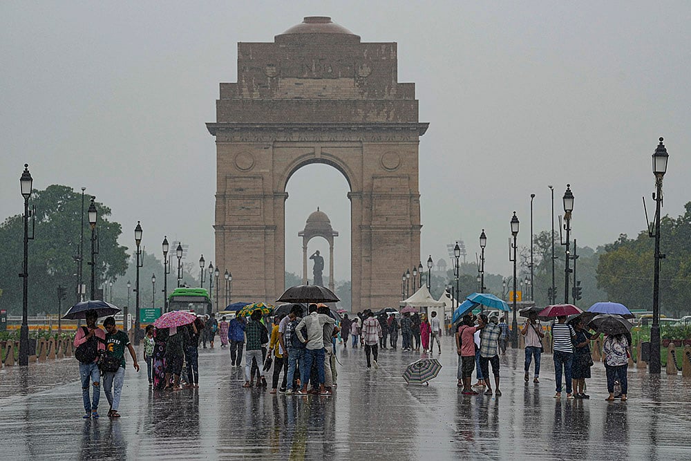 Visitors during rains at India Gate, in New Delhi