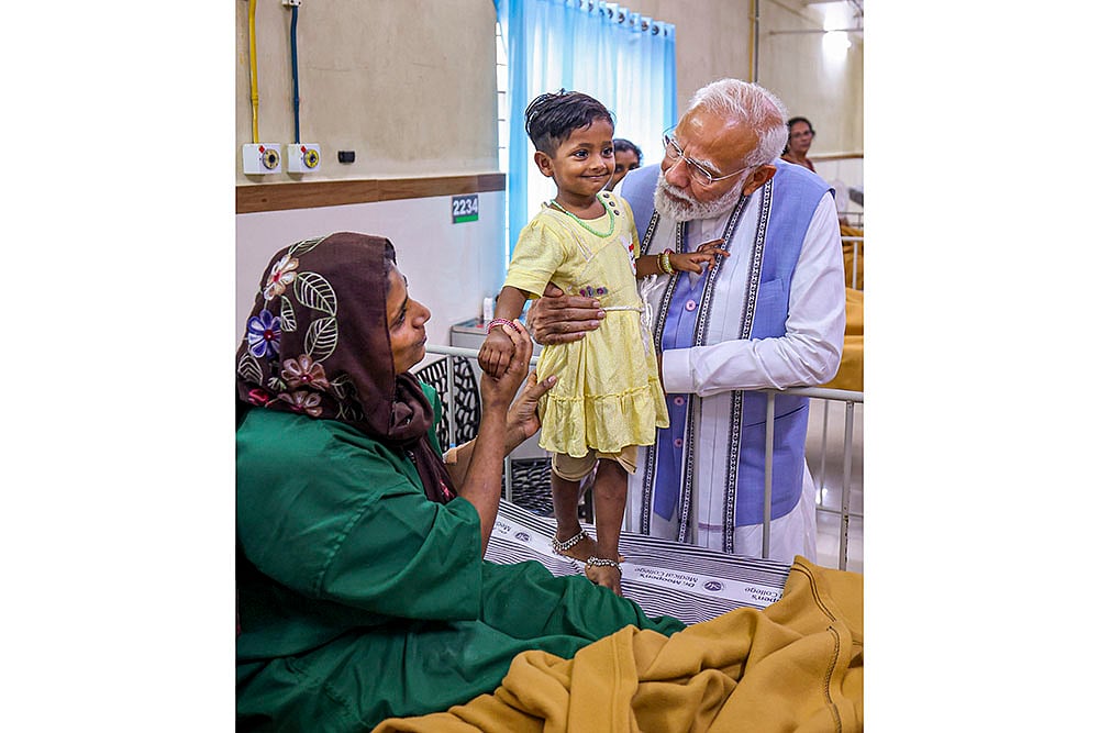 PM Modi Modi interacts with a child affected by the landslide, at a Hospital in Wayanad