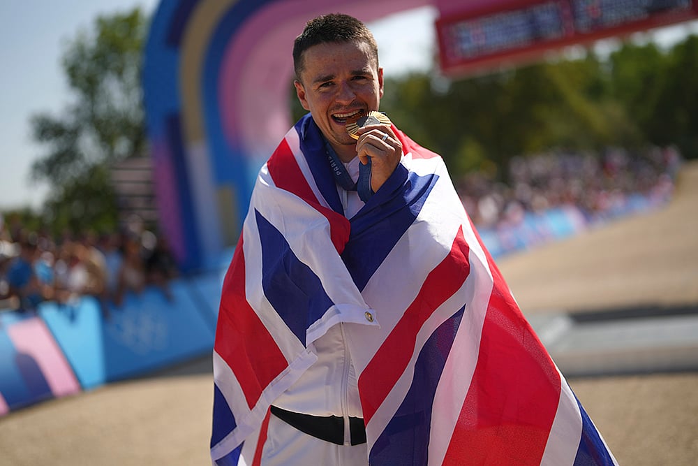 2024 Paris Olympics Mountain Bike Cycling medalists_Thomas Pidcock, of Britain, bites gold medal 