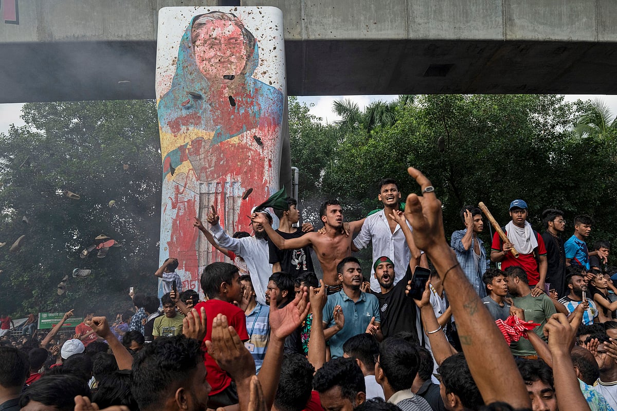 AP Photo : Protesters celebrate beside a defaced portrait of Prime Minister Sheikh Hasina after news of her resignation