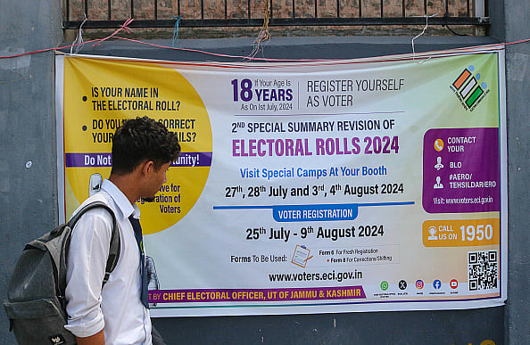 (Photo by Firdous Nazir/NurPhoto via Getty Images) : A student is looking at the Election banner as he is walking along a road in Srinagar, Jammu and Kashmir, on August 07, 2024. 