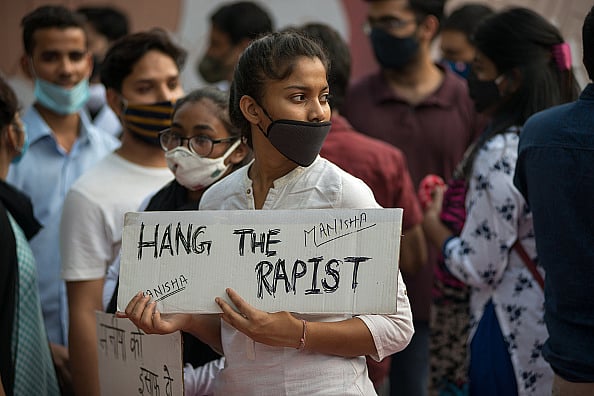 Getty Images : Young College girl holding a placard saying, hang the rapist