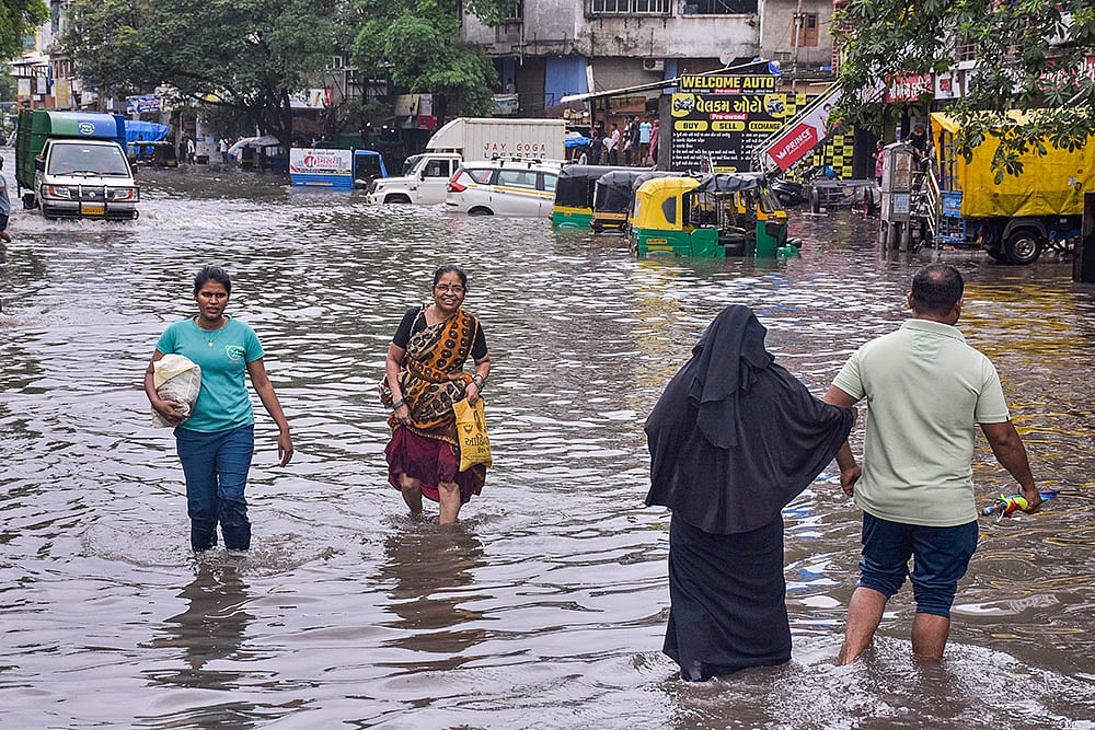 Gujarat Monsoon Rain and Floods_ People wade through a waterlogged road at Ved Darwaja in Surat