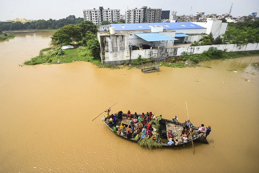 People travel using a boat across the swollen Ganga river in Patna