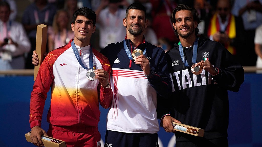 AP : Serbia's Novak Djokovic , center, gold medalist, Spain's Carlos Alcaraz, left, silver medalist, and Italian bronze medalist Lorenzo Musetti