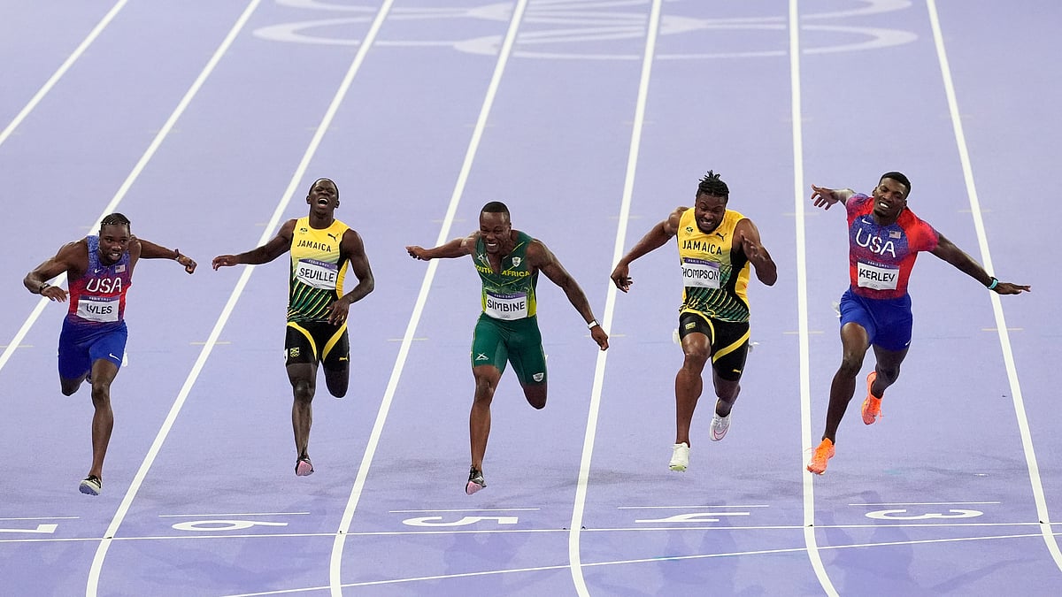 Martin Meissner/AP : Noah Lyles, of the United States, Oblique Seville, of Jamaica,Akani Simbine, of South Africa, Kishane Thompson, of Jamaica, and Fred Kerley, of the United States, cross the finish line in the men's 100 meters final at the 2024 Summer Olympics