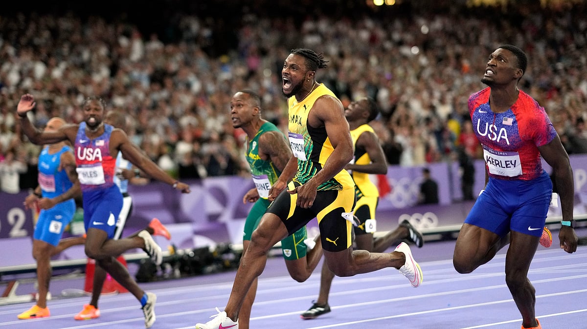 AP Photo/Bernat Armangue : Kishane Thompson, centre in the yellow suit, of Jamaica, reacts as he crosses the finish in the men's 100-meter final at the 2024 Summer Olympics.