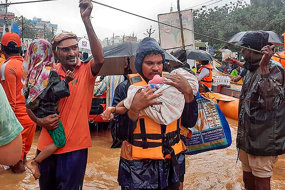 SDRF men rescue flood-hit people, in Ajit Singh Nagar in Vijayawada