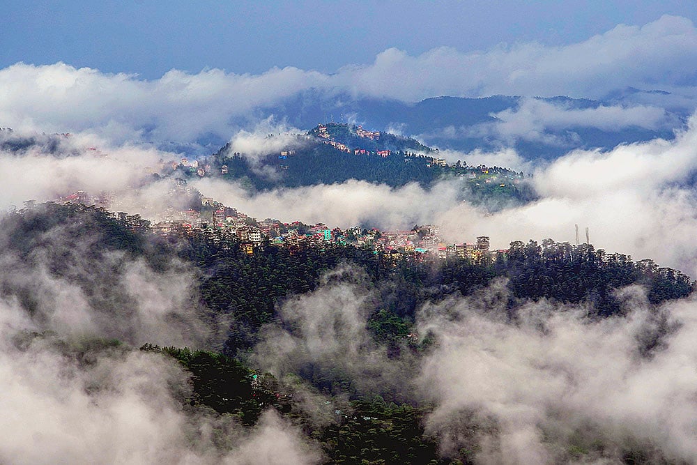 Low clouds cover the mountains after rainfall, in Shimla
