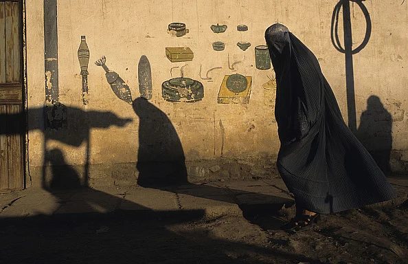 Woman in a burqa walking past a wall in Kabul Afghanistan