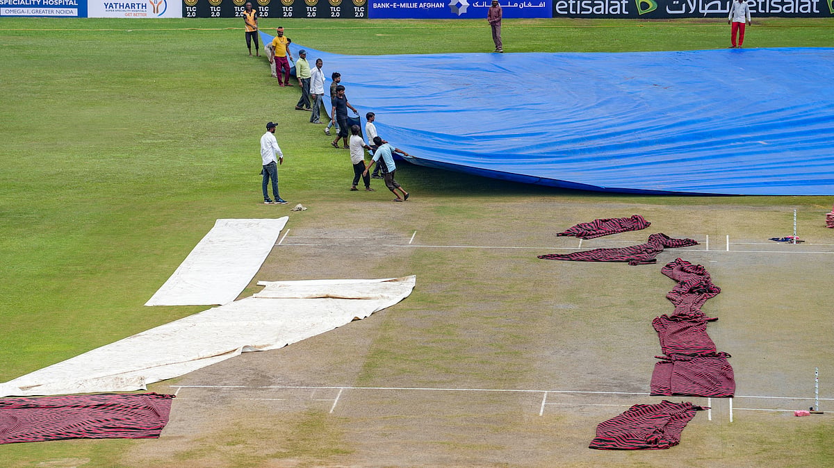 PTI/Kamal Kishore : Groundsmen remove the cover from the pitch on the second day of the one-off Test match between Afghanistan and New Zealand, in Greater Noida.