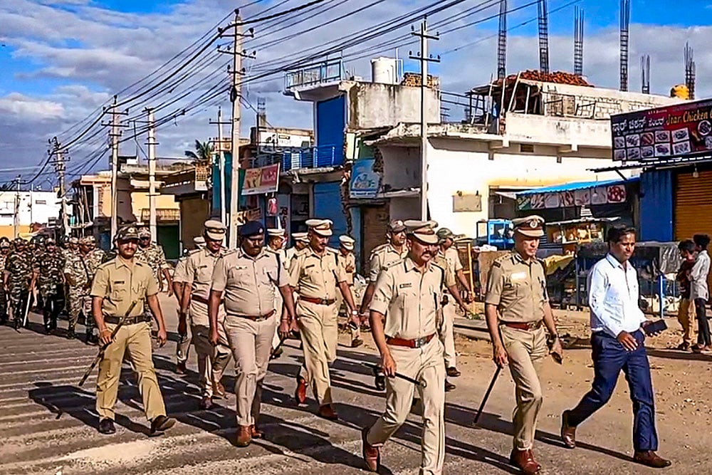 Police conduct a march following clashes between two groups in Nagamangala town