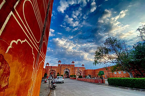 A breathtaking glimpse of Jaipur's iconic Ajmeri Gate under a dramatic morning sky