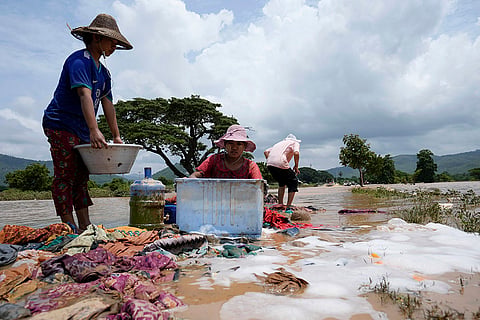 Myanmar floods: Local residents wash clothes along a flooded road