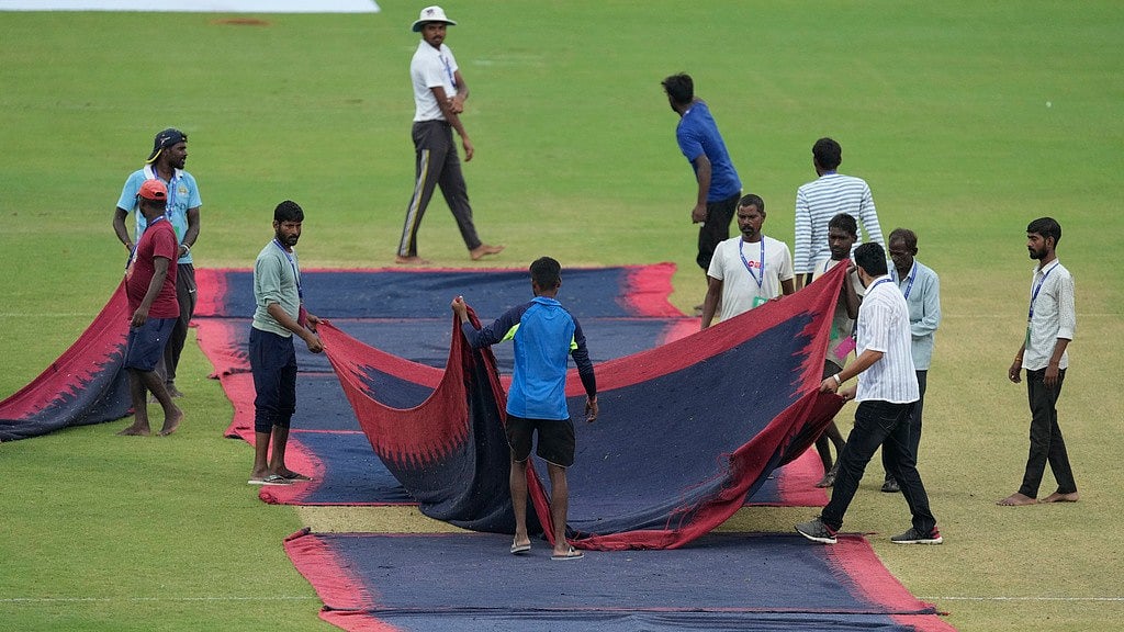 Photo: AP/Ajit Solanki : Ground staff covers the pitch amid rain on the first day of the second Test between Bangladesh and India in Kanpur.