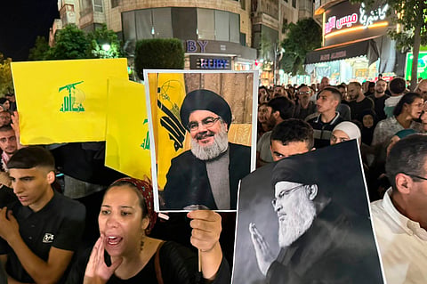 Palestinian protesters carry Hezbollah flags and posters with a picture of Hezbollah leader Sayyed Hassan Nasrallah during a rally in support of Hezbollah, in the West Bank city of Ramallah Saturday, Sept. 28, 2024
