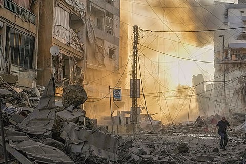 Mideast Tensions: A man runs for cover as a smoke raises in the background following an Israeli airstrike in Dahiyeh