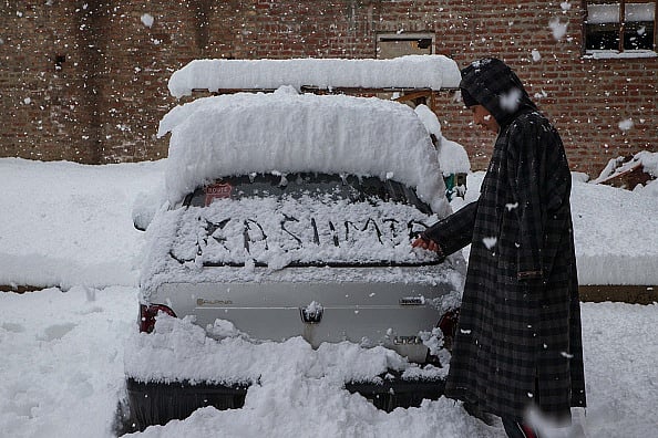 Kashmir beneath snow  : A man writes on the back window of a car during a heavy snowfall in Srinagar, Kashmir, India, February 22, 2022. 