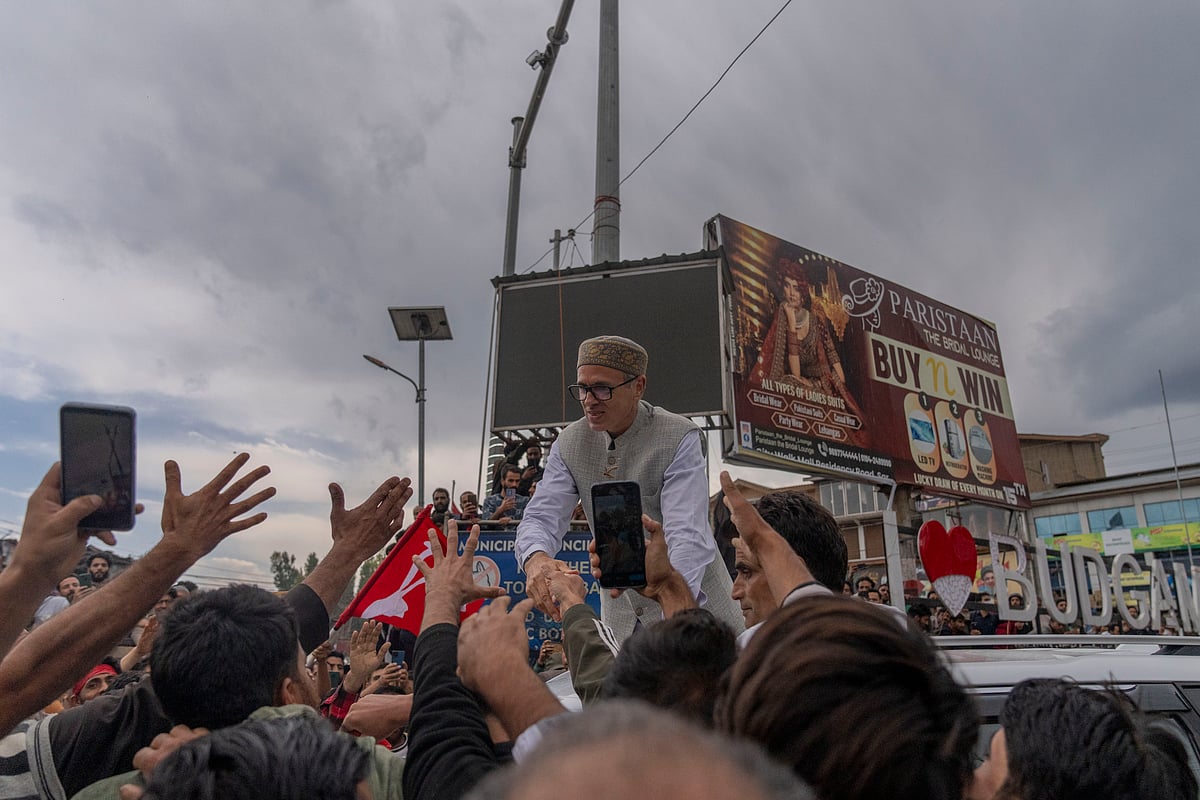 AP Photo/Dar Yasin : Jammu and Kashmir National Conference (JKNC) party leader Omar Abdullah, standing on car shakes hands with supporters as he celebrates his victory in the election for a local government in Indian controlled Kashmir, Budgam, Tuesday, Oct. 8, 2024. 