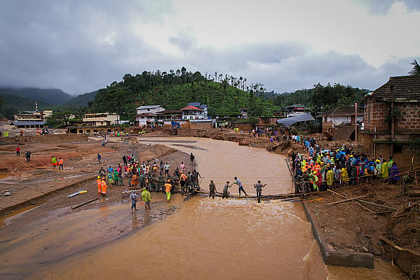 People cross a temporary bridge at the site of a landslide on July 31, 2024 in Chooralmala village.