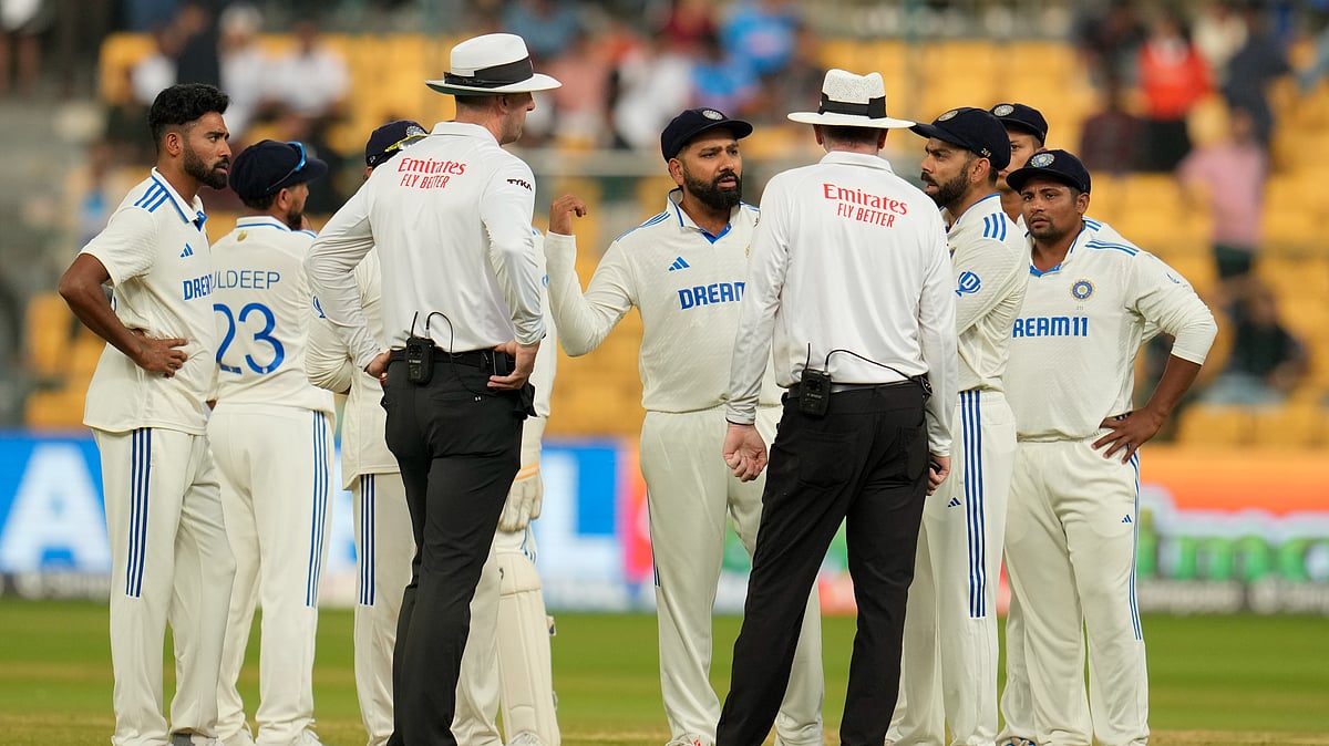 India's captain Rohit Sharma, centre, speaks to the umpires after bad light stopped play on day four of the first cricket test match between India and New Zealand at the M.Chinnaswamy Stadium. - AP Photo/Aijaz Rahi