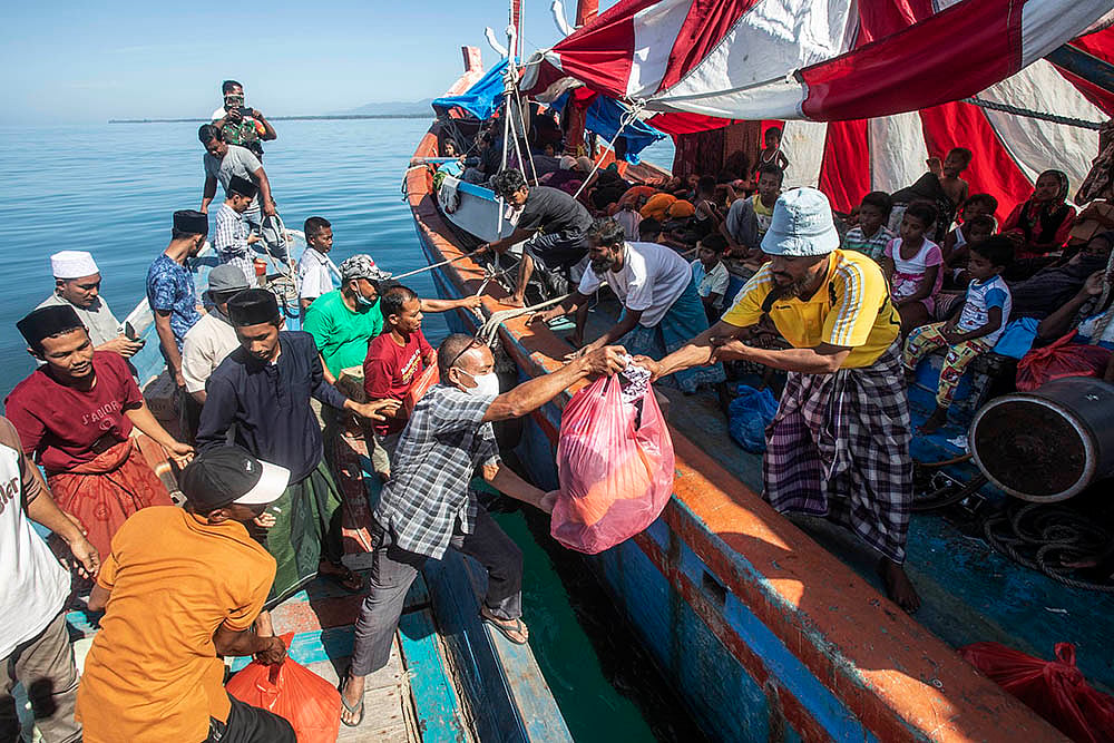 Rohingya refugees: Acehnese men, left, hand out relief goods for Rohingya Muslims