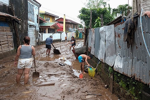 Tropical Storm Trami: Residents collect mud as they start cleaning their area