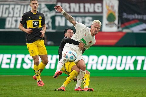 Bundesliga soccer: Augsburg's Phillip Tietz, right, challenges for the ball with Dortmund's Ramy Bensebaini