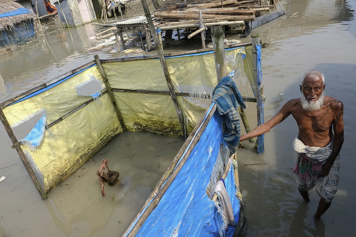 AP : An elderly man stands by a Tube well buried in water during high tide in Bangladesh
