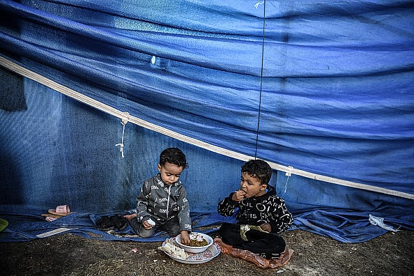 displaced Palestinian children around Nasser Hospital eat food distributed by volunteers