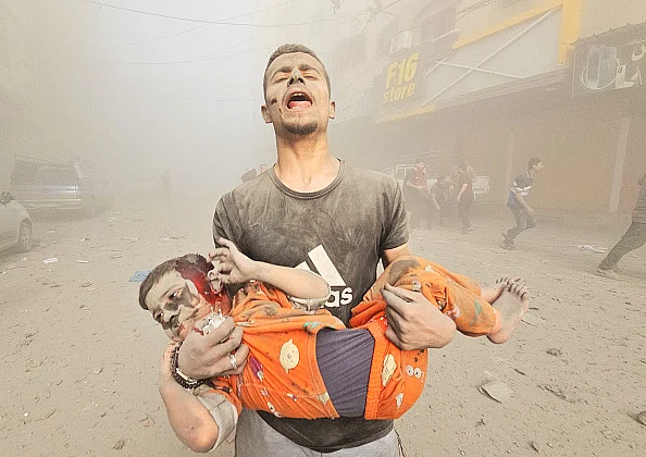 A man carries an injured Palestinian child as Israeli attacks continue