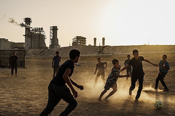 Children play soccer at sunset in proximity to the Ramat Hovav power plant in Wadi Al-Naam, Israel
