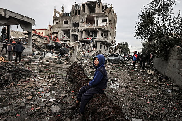 A boy sits on a fallen tree amid rubble after Israeli airstrike