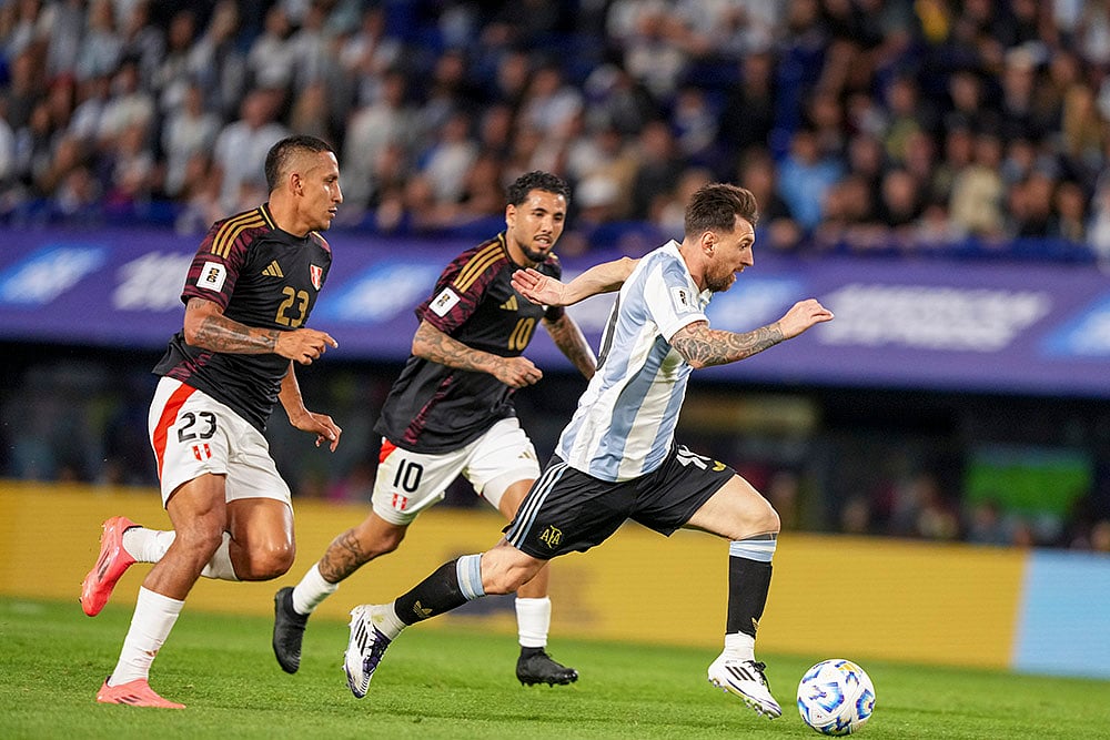 | Photo: AP/Natacha Pisarenko : Football World Cup 2026 Qualifiers: Peru's Alex Valera (23) and Peru's Sergio Pena chase Argentina's Lionel Messi 
