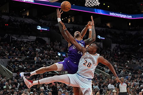 NBA: Jazz forward John Collins, top, is blocked by  Spurs center Charles Bassey (28)