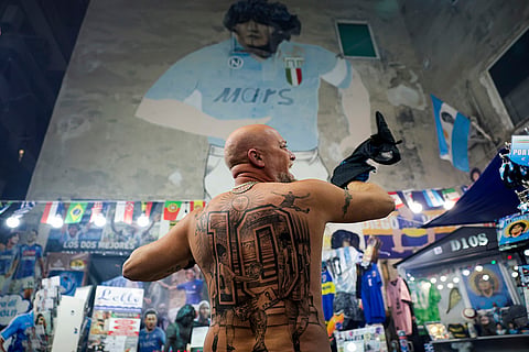 Italy Maradona death anniversary: A fan in front of a giant mural of Maradona