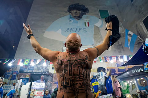Italy Maradona death anniversary: A fan opens his arms in front of a giant mural of Maradona 