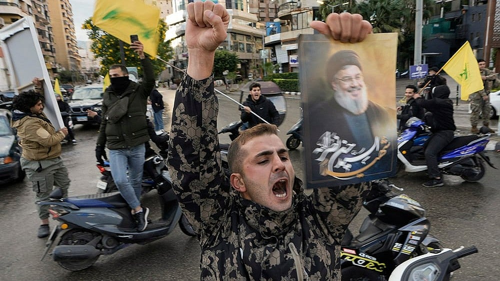 Israel Lebanon Ceasefire: A man celebrates carrying a picture of slain Hezbollah leader Hassan Nasrallah - | Photo: AP/Bilal Hussein