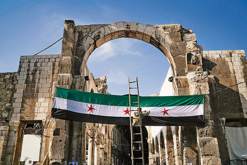 A worker sets up a Syrian “revolutionary” flag at the entrance of a mosque in Damascus