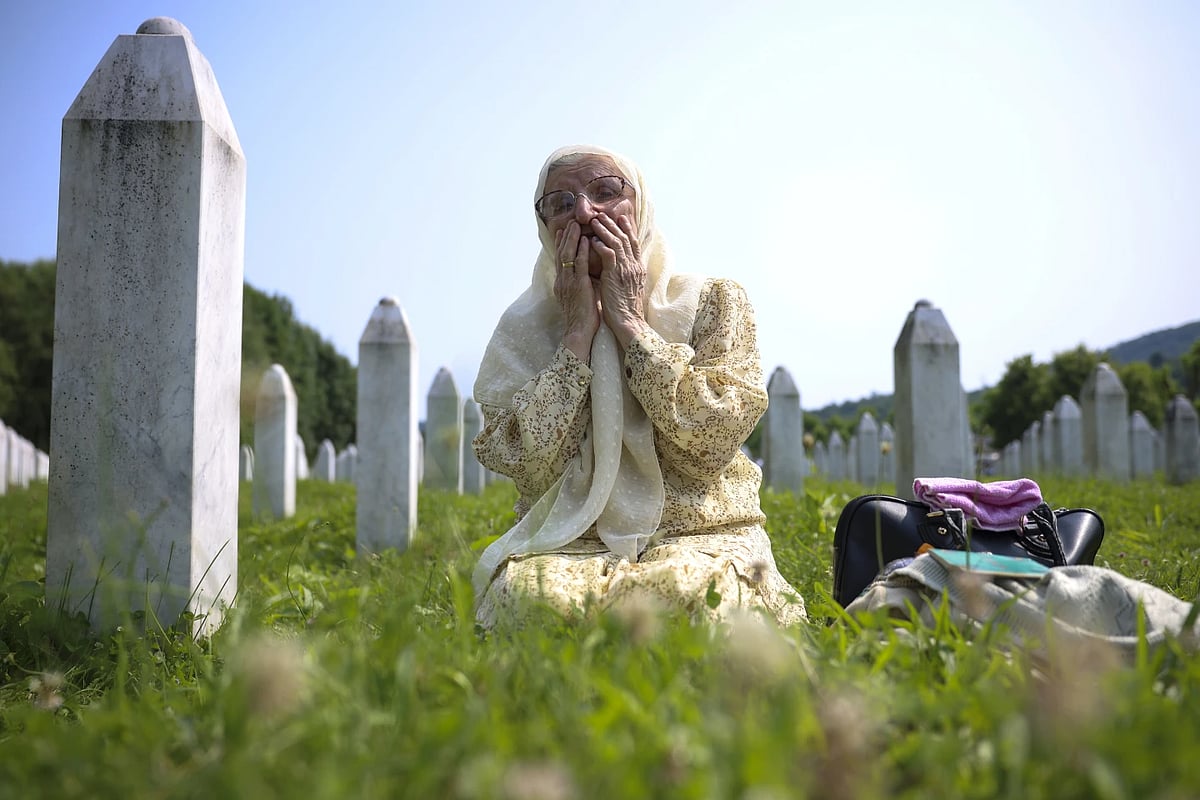 AP : A Bosnian muslim woman mourns next grave of her relative, victim of the Srebrenica genocide, in Memorial Centre in Potocarı, Bosnia, Tuesday, July 11, 2023 |