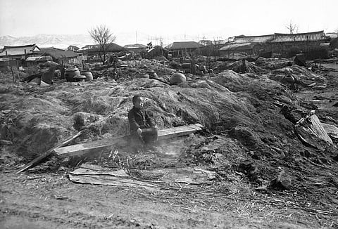 A Korean child sits in smoldering ruins of his home destroyed by fire in the Suwon area on February 3, 1951, as allied troops burned dwellings which might provide shelter for red troops |
