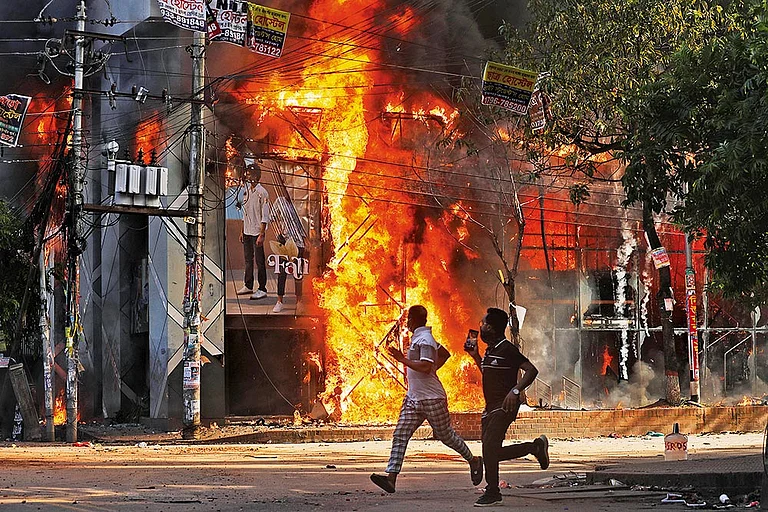 Waves of Unrest: People run past a shopping centre, which was set on fire in Dhaka, Bangladesh, in August 2024 - | Photo: AP