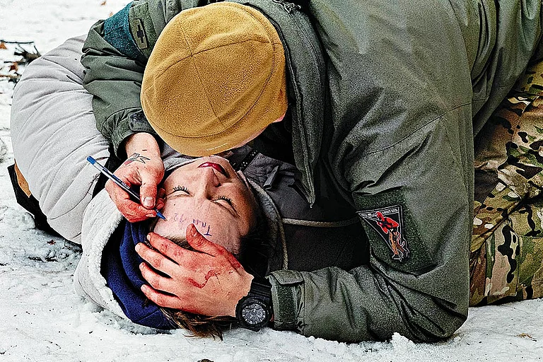From Ground Zero: A soldier puts a timestamp on the forehead of a woman who was seriously injured in the sudden Russian shelling in Kramatorsk. The timestamp signifies the time he applied the first aid before she could be rushed to the hospital for further treatment - Photo: Carlo Cozzoli/Memora